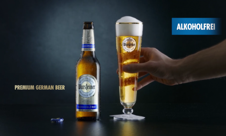 Warsteiner Alkoholfrei flesje en hand die het glas vastpakt